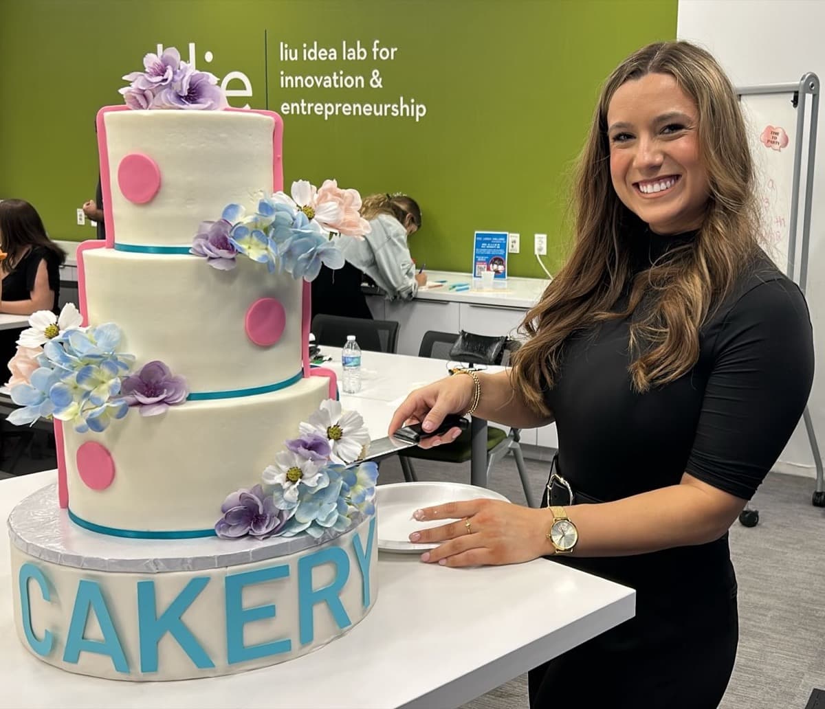 Mackenzie Ford cutting a three-tier Cakery cake at the launch party
